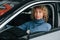 Sitting at driver`s seat. Woman with curly blonde hair is in autosalon