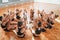 Sitting on the floor. Group of female kids practicing athletic exercises together indoors