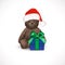 Sitting fluffy cute brown teddy bear with red christmas santa claus hat and blue gift box with green bow. Children`s toy isolated