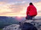 Sitting hiker on rock. Man in red black warm clothes is sitting on cliff and enjoying far view.