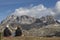 Sitting people on the grass who are looking into the landscape in the Italian Dolomites under the Tre Cime mountain. The sun is