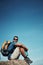 Sitting on top of the world. Portrait of a carefree young man taking a quick break from hiking up a mountain during the