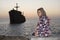 Sitting woman with greek ship wreckage in kish island after sunset