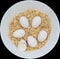 Six Bantam white eggs on brown Sawdust with one being crack egg, which they are in a round white bowl.