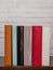 Six books of different colors resting on a dark wooden shelf