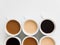 Six cups of coffee of different colors on a white background
