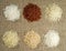 Six heaps of rice of different varieties on the background of sacking