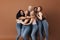 Six laughing women of a different race, age, and figure type. Group of multiracial females having fun against a brown background