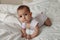 A six month old baby in light pink crawls on the white bed