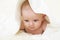 Six months old baby with a towel after taking a bath, in bed at home. Little baby under a white towel