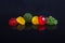 Six multi-colored fruit-paste sweets on the black reflecting su