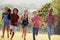 Six pre-teen friends running in a park, front view, close up