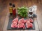 Six raw lamb chops on a slate plate, Infused oils , herbs, salt and pepper shaker on a wooden table surface