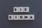 Six Sigma word made of square letter word on grey background