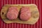 Six simple beef uncooked burgers on a wooden board and red and white butcher apron. Meat industry product. Fast fool meal