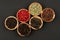 Six small wooden bowls filled with various peppercorns