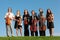 Six violinists stand on grass against sky