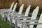 Six white Adirondack chairs on manicured lawn