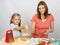 Six-year girl helps mother to rub grated cheese