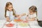 Six-year girl observes and controls her younger sister puts on pizza ingredients