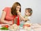 Six-year girl with pigtails giving mom bite out of a piece of cheese at the kitchen table where they cook together