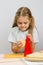 Six-year girl posing at kitchen table with cheese and a grater in the hands of