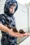 Six-year-old boy in a gray jacket with a hood keeps four snails on his hand.