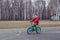 Six-year-old boy in warm clothes riding a green bike