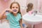 Six year old girl brushing her teeth and turned away from the sink looks in the picture
