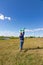 A six-year-old preschooler boy in a blue jacket launches a toy plane in a field against a blue sky with clouds on a summer day