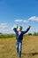 A six-year-old preschooler boy in a blue jacket launches a toy plane in a field against a blue sky with clouds on a summer day