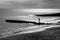 A six year old unrecognisable boy walking along a jetty in the sea, black and white photograph