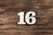 Sixteen 16 - White wooden number on rustic background