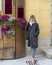 Sixty-five year-old female Korean tourist enjoying a sidewalk flower display in Pitigliano, Italy.