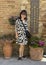 Sixty-five year-old female Korean tourist posing amoung flowers along the street in Montepulciano, Italy.