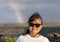 Sixty-three year-old female Korean tourist standing with a rainbow in the background in Hawaii Volcanoes National Park.