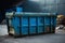 The sizeable blue dumpster, a robust iron container built for waste transportation