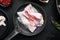 Sizzling bacon pieces in cast iron frying pan  on black background  top view flat lay