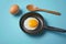 Sizzling fried eggs in pan, wooden spoon centerpiece, blue background