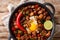 Sizzling spicy pork sisig with egg ang lime close-up in a pan. Horizontal top view