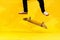Skateboarder performing skateboard trick - kick flip on concrete. Olympic athlete practicing jump on yellow background in the