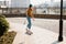 Skateboarding Woman In The City. Skater girl in denim is riding her board on the square. Athletic Woman skateboarder. Building on