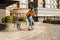 Skateboarding Woman In The City. Skater girl in denim is riding her board on the square. Athletic Woman skateboarder. Building on