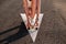 Skater girl sitting on board in the street on arrow road marking backlit by sunset light