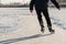 Skater legs at skating rink. Man skating on white ice on frozen lake. Back view. Winter leisure activity