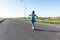 Skater Young woman from the back in blue jeans and a t-shirt skateboarding on the road in summer