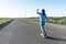 Skater Young woman from the back in blue jeans and a t-shirt skateboarding on the road in summer