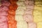 Skeins of cotton yarn of in yellow-pink color spectrum on shelf in specialty craft store