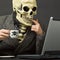 Skeleton drinks poisonous coffee with laptop