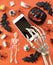 Skeleton using smartphone. Halloween decorations on orange  background